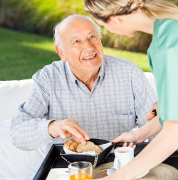 caregiver giving meal to an elder