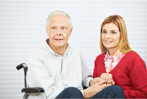 Senior men in wheelchair with caregiver holding his hands