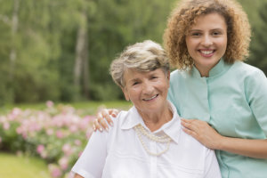 caregiver smiling with her senior patient in the park