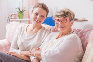 elder woman sitting on a couch with her caregiver
