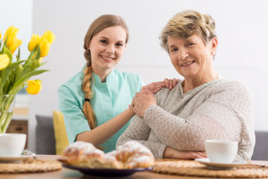 senior women sitting and caregiver smiling